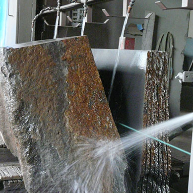 Débitage d'un bloc de basalte au fil diamanté dans l'atelier